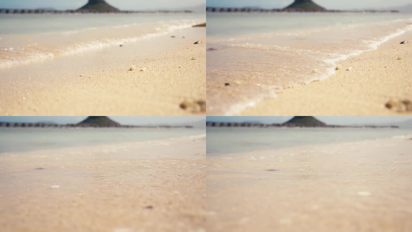 沙滩上的沙子特写，小波浪和水冲进画面
