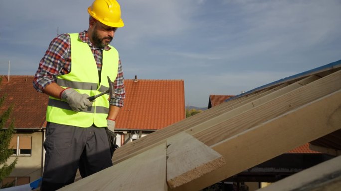 白人男性屋顶工人，在建筑工地的屋顶梁上工作