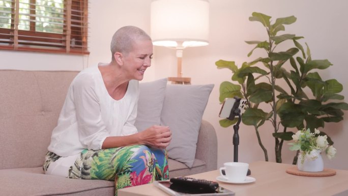 快乐的老女人在沙发上放松，用社交媒体发视频