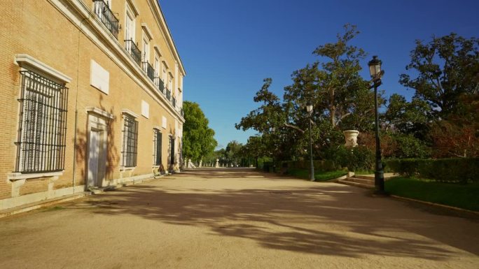 马德里阿兰胡埃斯大皇家花园的入口，那里有长椅和大树，树枝间透着阳光。