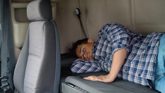 印度卡车司机在长途加班后睡在自己的小屋里。睡眠不足