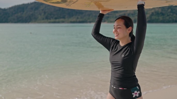 手持冲浪板的女子走在海滩上