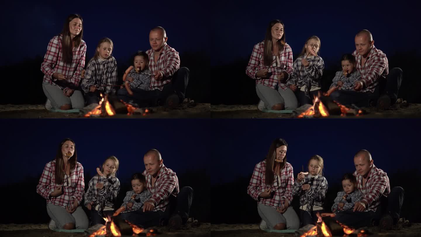 深夜，一家人在湖边露营，在篝火里煮香肠