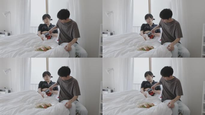 年轻的日本夫妇在床上吃早餐