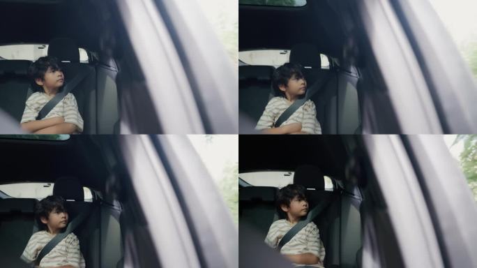 一个亚洲男孩坐在汽车后座上放松，望着窗外去海边的路