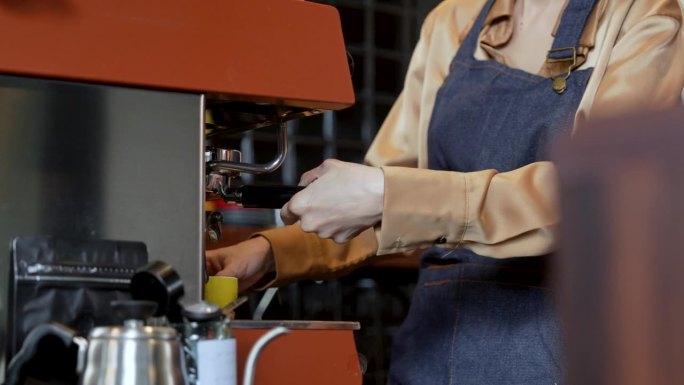 从咖啡机倒入咖啡杯。女咖啡师用滤嘴制作双倍意式浓缩咖啡。新鲜的咖啡。小企业主，创业。