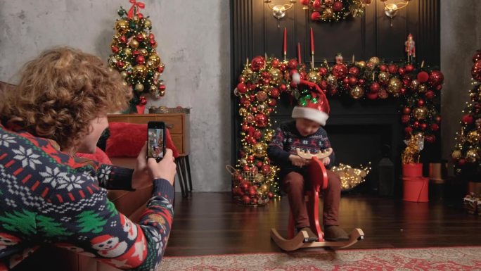 一位年轻的父亲用智能手机拍下了儿子在圣诞现场玩耍的照片