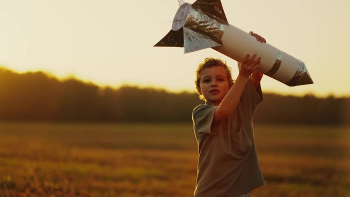 夏天，可爱的小男孩在大自然中玩纸和锡箔做的玩具火箭，慢动作