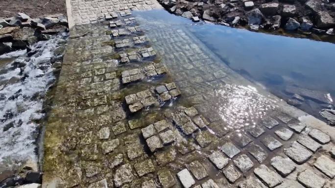 这条土路穿过一条小溪，这条小溪穿过河流，在洪水无法通行时继续前进。修复河道，将农田垂直排水改道