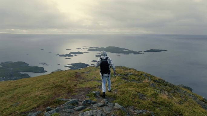 年轻的男性探险家走向悬崖边缘，观察斯堪的纳维亚迷人的全景风光