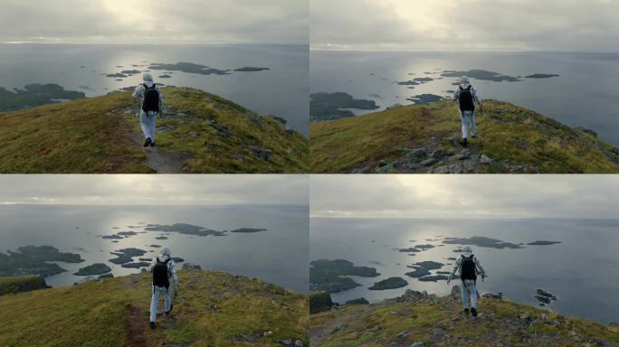 年轻的男性探险家走向悬崖边缘，观察斯堪的纳维亚迷人的全景风光