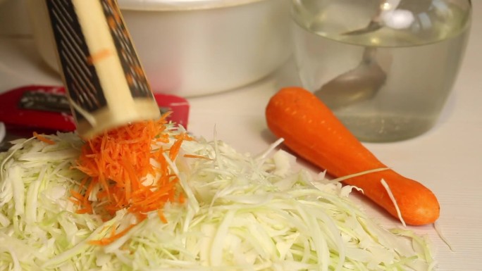 一个男人在家煮酸菜。磨胡萝卜。特写，从侧面看。