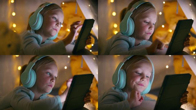 耳机，孩子晚上在家帐篷里用平板电脑打字，社交媒体应用程序，音乐或卡通。科技，女孩或孩子听收音机，听音