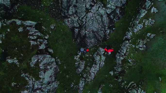 两个人一起用北欧拐杖徒步旅行。爬上一个巨大的岩石覆盖的田地