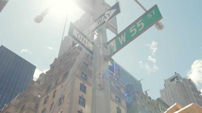 纽约市灯柱上悬挂的多个彩色街道标志的低角度镜头。单行道，西55街，酒店装货区。旅游理念，夏日旅游