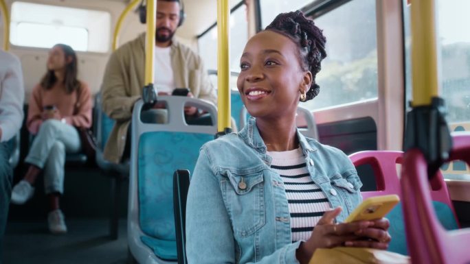 黑人女性在公交车上带着手机，笑着在城市通勤路上开车时带着微笑。公共交通，服务或骑行，快乐女孩思维和移