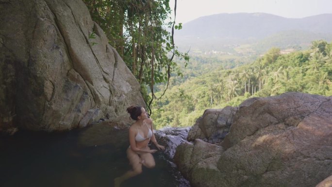 女子在苏梅岛的热带瀑布中游泳