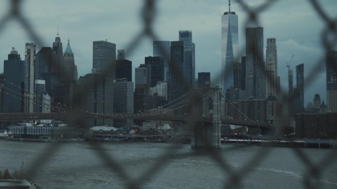 曼哈顿大桥围栏后的手持镜头。下午的纽约市景。历史和现代摩天大楼，布鲁克林大桥上的交通
