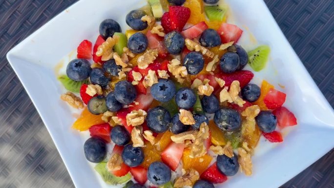 健康早餐草莓，覆盆子，蓝莓，猕猴桃，橙子，坚果配蜂蜜和酸奶。健康美味的食物。