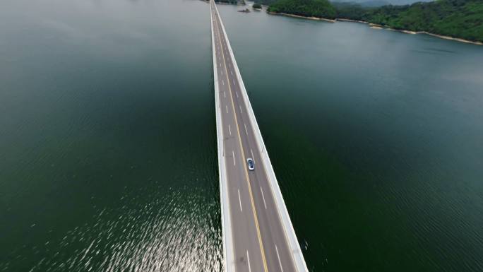 穿越机航拍新能源汽车行驶在湖面大桥上