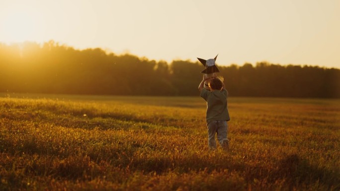 暑假在农村，小男孩玩着手工制作的玩具火箭，在田野里奔跑