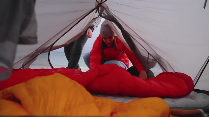 一对浪漫的夫妇穿着暖和的衣服在寒冷的天气里露营。进入帐篷