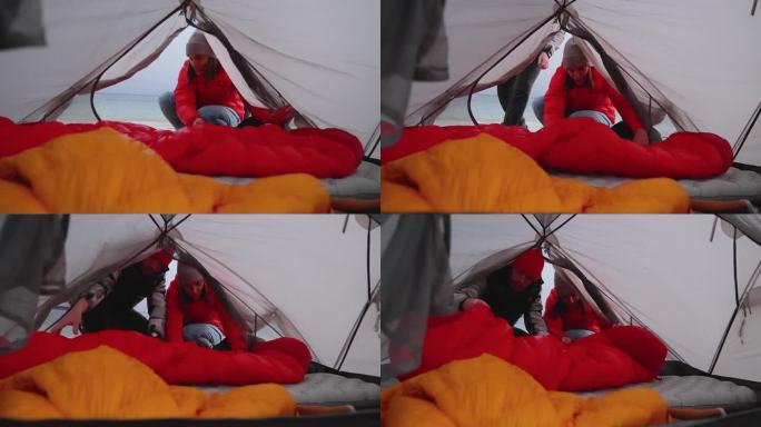 一对浪漫的夫妇穿着暖和的衣服在寒冷的天气里露营。进入帐篷