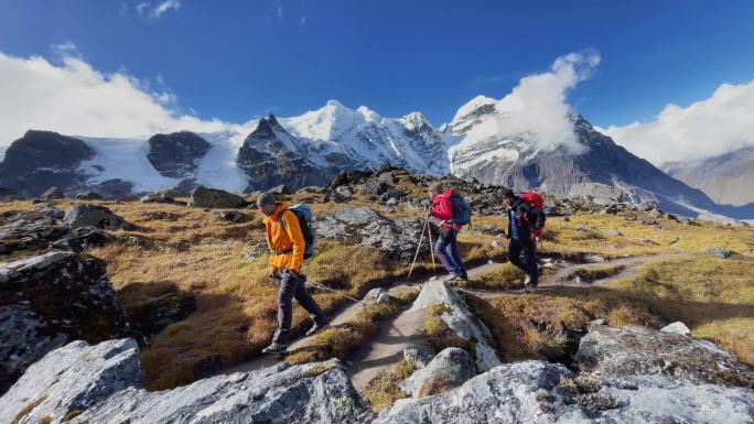 三名探险队员背着背包，沿着卡雷附近的马卡鲁巴伦公园徒步旅行路线行进。攀登梅拉峰适应步行。背包客用登山