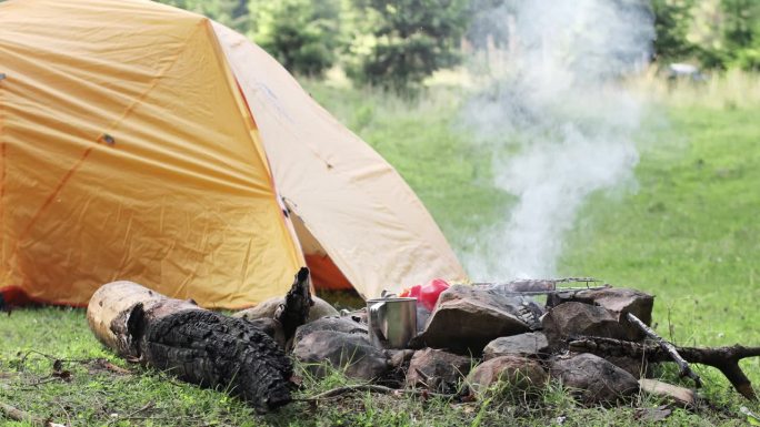一个人在帐篷附近准备美味的烤肉串。用大量的烟烤串的过程。在大自然中烹饪。