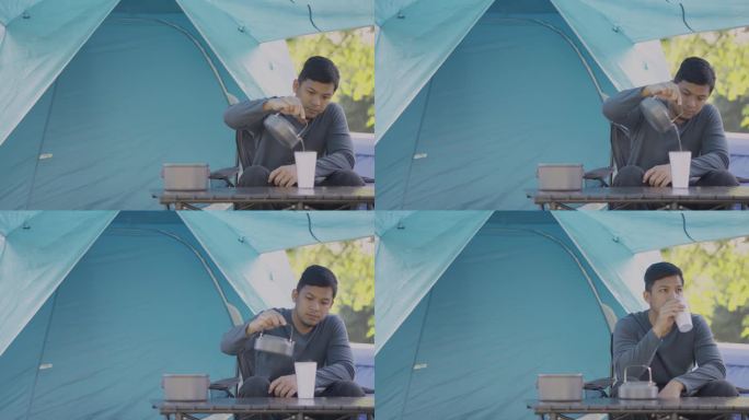 早上在露营地，亚洲男旅行者坐在野营椅上喝咖啡。