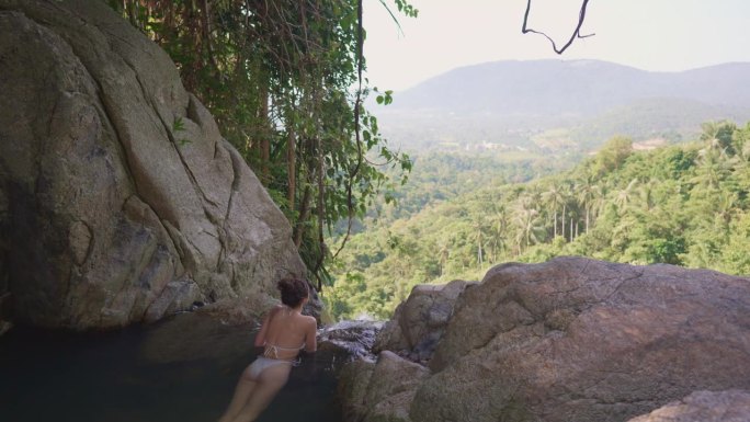 女子在苏梅岛的热带瀑布中游泳