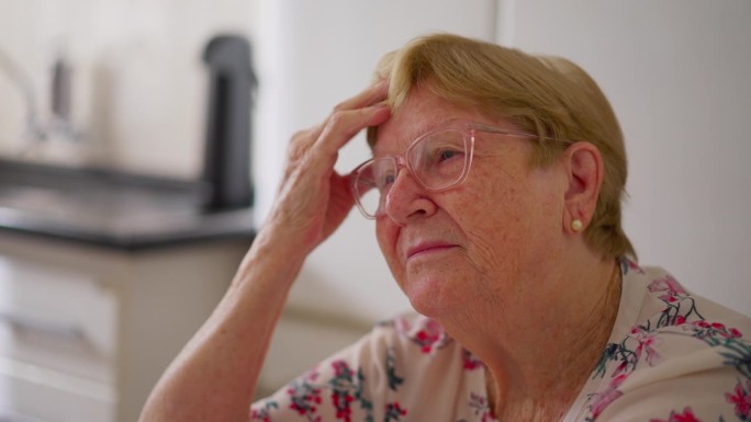 老年妇女沉思的脸部特写，手放在额头上，思考。忧心忡忡的80多岁老人在反思过去的经历