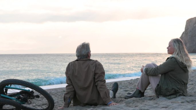 成熟的夫妇在空旷的沙滩上骑自行车放松