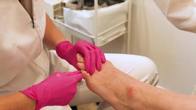 在Spa沙龙接受古典足疗的女性腿部，切割脚指甲角质层。腿部和指甲皮肤护理。足疗程序和SPA过程。特写