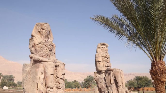 在埃及卢克索的门农巨像中，两座以山脉为背景的法老巨型雕像的废墟