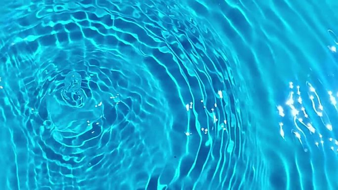 散焦模糊透明蓝色水滴表面纹理与飞溅反射。新潮抽象的自然背景。水波在阳光下与复制空间。蓝色水彩光泽。