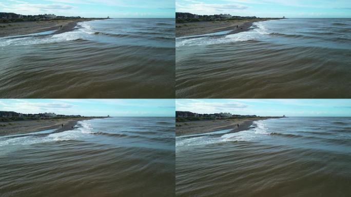 狗在扔石头后跑进浑浊的爱尔兰海。慢动作半速。弗利特伍德，兰开夏郡，英格兰，英国
