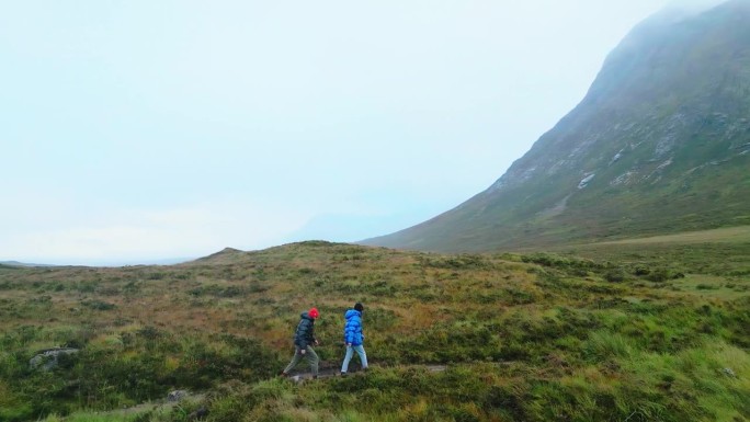 两个人一起用北欧拐杖徒步旅行。欣赏美丽的自然风光，绿草如茵，步道优美