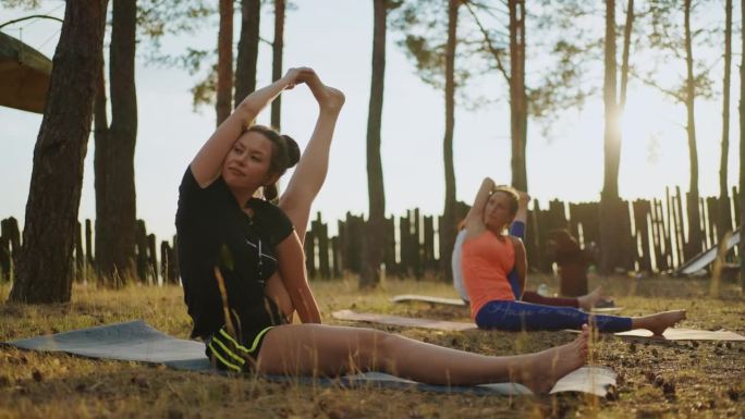 成年女性在瑜伽营训练，运动女性练习体式伸展身体