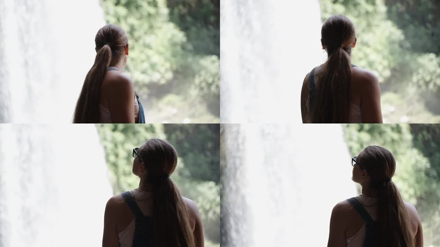 一位身穿牛仔连衣裙的年轻女子正在欣赏森林中山间河流中的瀑布。