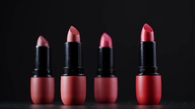 黑色背景上的红色唇妆，不同深浅的粉色青铜色口红，工作室广告宏观美容理念。