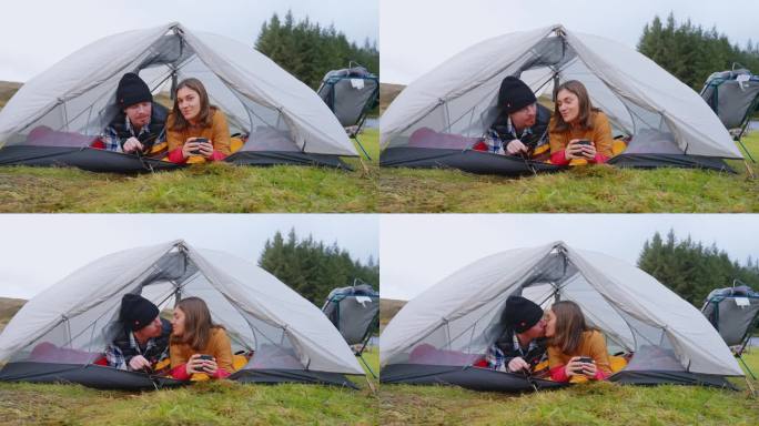 一对浪漫的夫妇穿着暖和的衣服在寒冷的天气里露营。在帐篷里放松