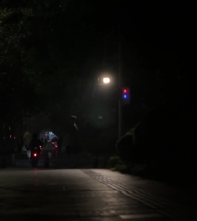 夜晚凌晨路灯下的行人骑电动车夜间路人