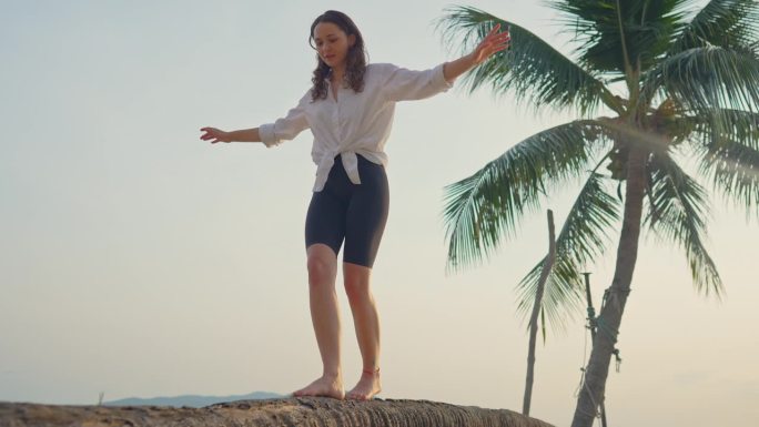 一个女人在沙滩上的椰子树上散步