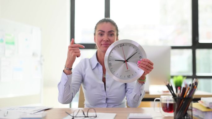 女人用食指指着坐在办公桌前工作的二十四小时