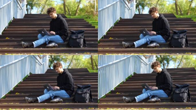 一个年轻人坐在城市公园的楼梯上，一边用笔记本电脑打字。秋天的季节。教育，工作理念。实时概念。