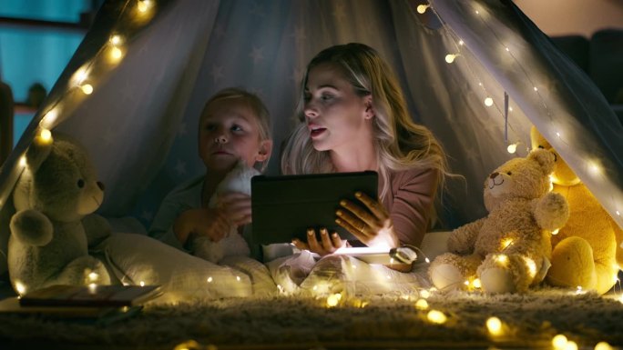 平板电脑，母女俩在客厅的帐篷里过夜，晚上在家里的灯下看书放松。孩子们在黑暗的房子里露营，在公寓里和妈