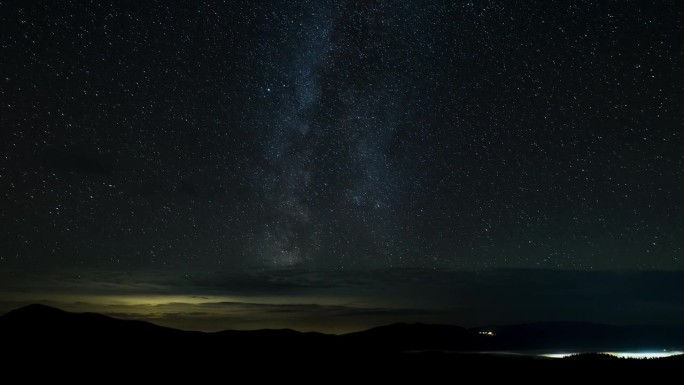 银河的时间流逝在星夜的群山和云层之上移动