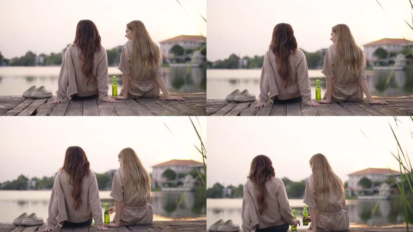 两个美女在湖边边聊天，边喝啤酒，一起露营。