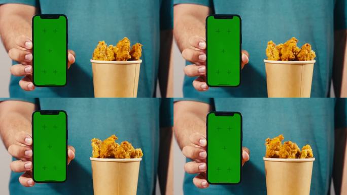 手机外卖应用带色度键绿屏，餐点鸡块和炸鸡薯条，放在木桌上即可外卖。肥美的美国菜。